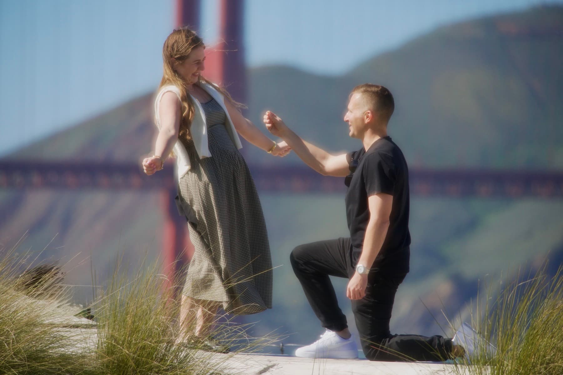 Thomas proposing to Victoria in the Presidio, with the Golden Gate Bridge behind them.